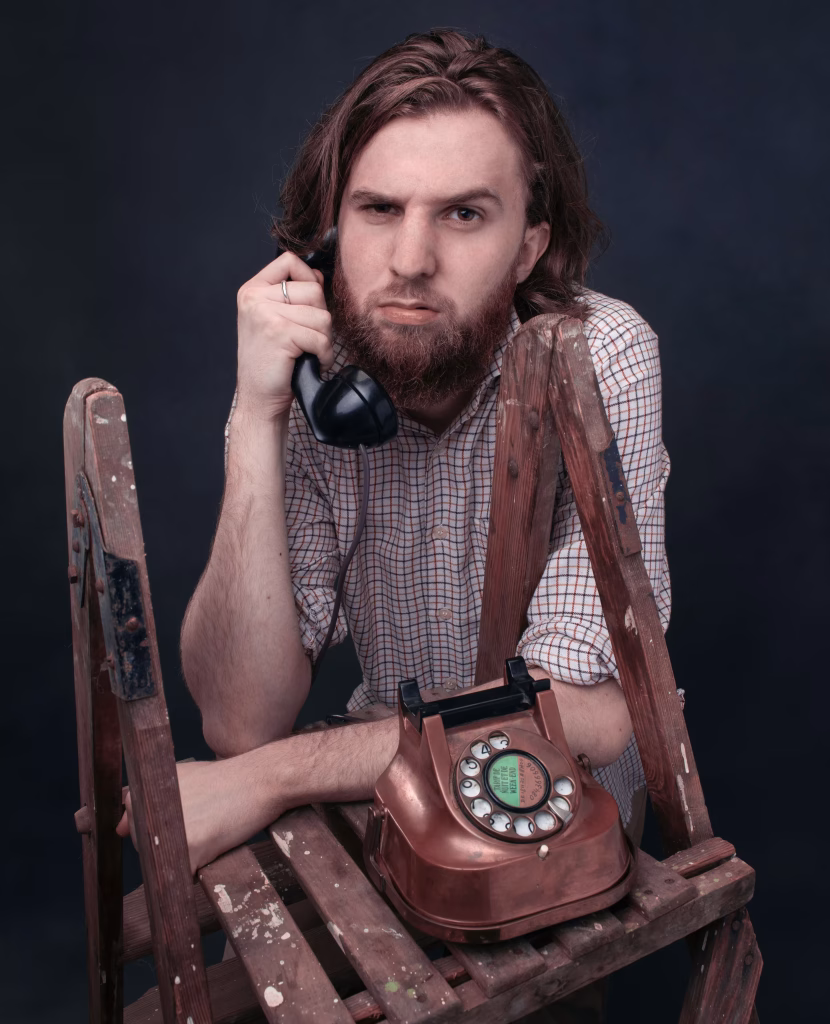George holding an old rotary phone with a frown